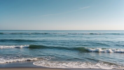 Calm ocean waves rolling onto a sandy beach under a clear blue sky with copy space for text