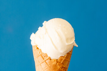 Milk ice cream in a waffle cone, with blue background
