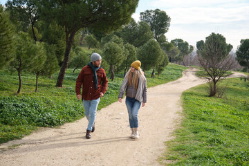 Young couple walking on a path and talking during a winter walk in a park