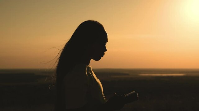 girl prays with bible her hands sunset. young girl asks for help. read prayer dawn. human faith dream. ask sky. relaxation concept. happy person lives faith. good book helps find way. pray park sun