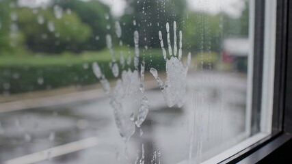 Raindrops trickling down windowpane, revealing haunting handprints symbolizing emotional entrapment and silent struggle within domestic environment