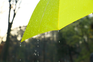 Open yellow umbrella under pouring rain outdoors, closeup