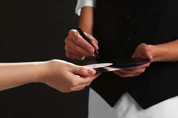 Singer signing autograph on vinyl record against black background, closeup
