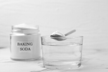 Glass of water and baking soda on white marble table, selective focus