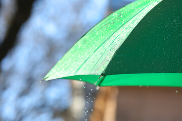 Open green umbrella under pouring rain outdoors, closeup