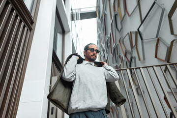 Fashion handsome urban man in stylish casual clothes with sunglasses walking on the street near...