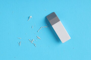 One eraser and scraps on light blue background, top view