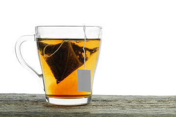 Tea bag in glass cup with hot drink on wooden table against white background. Space for text