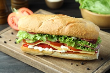 Delicious baguette sandwich with salami and cheese on grey wooden table, closeup