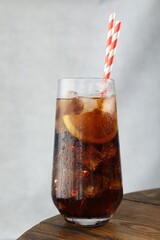 Refreshing iced cola with lemon slices on wooden table