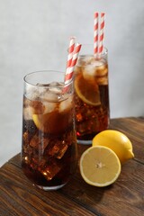 Refreshing iced cola with lemon slices on wooden table