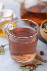 Delicious herbal tea and dry leaves on grey table, closeup