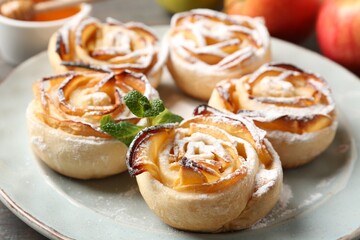 Freshly baked apple roses with mint on table, closeup