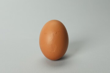 One egg with cracked shell on grey background, closeup