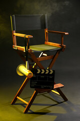 Director's chair with clapperboard and megaphone on dark background with smoke