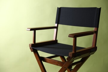One empty director's chair on pale olive background, closeup. Space for text