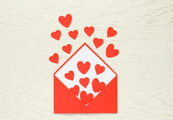 Valentine's Day. Envelope with many paper hearts on white wooden background, top view