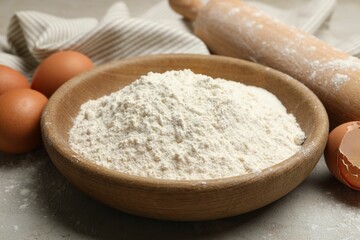 Rolling pin, flour and eggs on light grey background, closeup