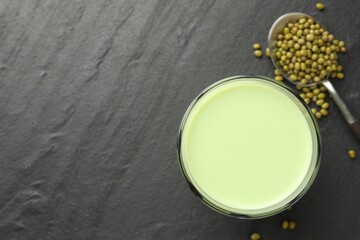 Fresh mung bean juice in glass and seeds on black table, flat lay. Space for text