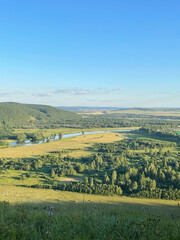 Beautiful daytime natural landscape with a view of the village houses and the river in the distance, the sky is clear and clear