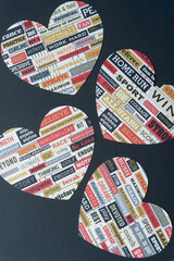 four decorative hearts machine-cut from sports-themed scrapbooking paper and arranged on black paper