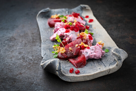 Red herring salad with pickled herring, red beets and walnuts served with a creamy sauce as close-up on a design plate