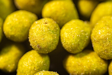 Extreme close-up of green-coated peanuts with a textured layer of seasoning and visible salt crystals. The macro perspective highlights the crunchy coating and rich flavor details.