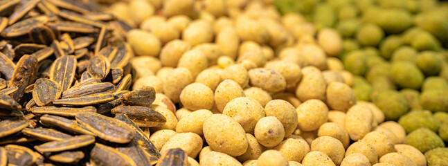 A detailed close-up of spiced roasted sunflower seeds and crunchy peanuts. The contrasting textures and colors highlight the variety of crunchy, tasty snacks.
