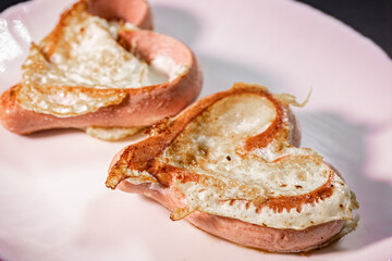 A close-up of heart-shaped sausages stuffed with a fried egg on a white plate. The dish has a golden brown crispy texture, making for a creative and delicious breakfast presentation.