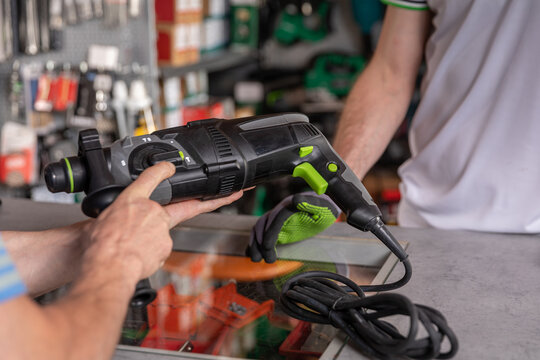 A buyer is currently examining a power tool inside the hardware store to assess its features