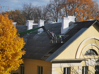 Worker on aerial platform restore, repair the roof. No AI tools