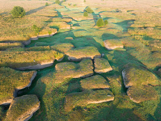 Unique karst landscape in Estonia: A drone captures the intricate patterns of a dried riverbed amidst lush green hills, showcasing the captivating beauty of this geological formation.