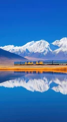 Scenic train journey across a serene landscape reflected in a pristine lake and snowy mountains