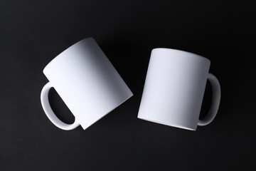 Two blank white mugs on black background, top view. Mockup for design