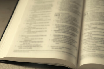 Fototapeta premium Open Holy Bible in English language on beige table, closeup