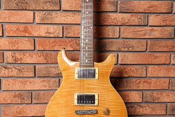 Fototapeta premium One modern electric guitar near brick wall, closeup