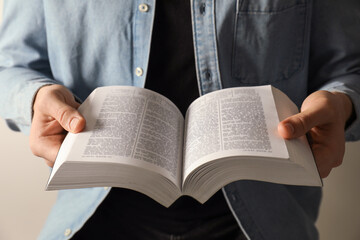 Fototapeta premium Man reading Holy Bible in English language on light background, closeup