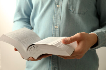 Man reading Holy Bible in English language on light background, closeup