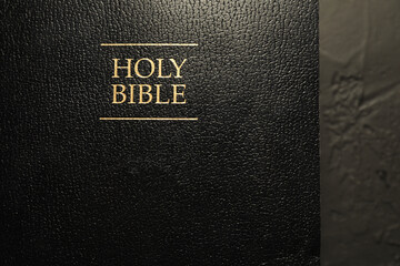 Hardcover Holy Bible in English language on black table, top view