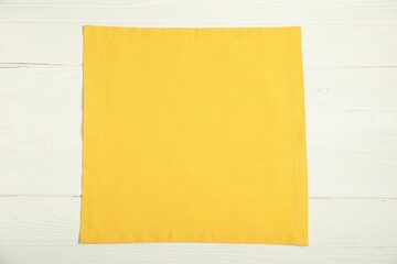 Yellow napkin on white wooden table, top view