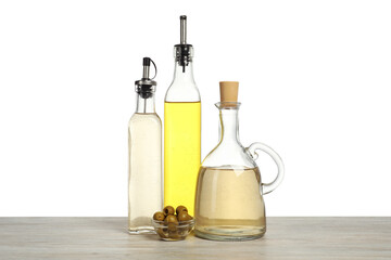 Salad dressings and olives on wooden table against white background
