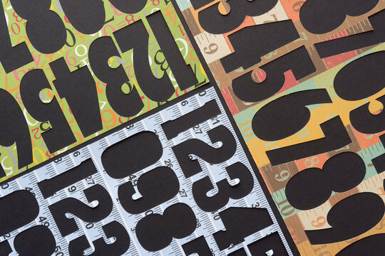 decorative paper stencils with machine-cutouts featuring numbers arranged in geometric form on black paper