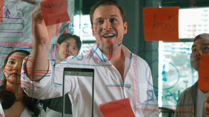 Portrait of professional business team brainstorming marketing idea by using sticky notes to share creative idea at glass wall. Group of diverse business team discuss about strategy. Manipulator.