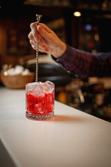 Bartender Stirring a Classic Red Cocktail in an Elegant Glass at a Cozy Bar