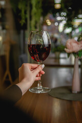 Woman Holding a Glass of Red Wine in a Cozy Restaurant with Ambient Lighting