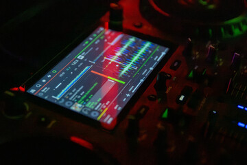 Fototapeta premium DJ Equipment Featuring a Colorful Audio Waveform Display in a Nighttime Setting and Atmosphere