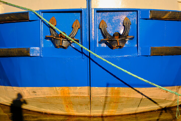 Naklejka premium Anchors on blue ship hull with rope shadow