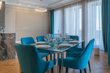 Stylish interior of the dining room in a luxury apartment. Elegant table setting. Blue upholstery of the chairs.