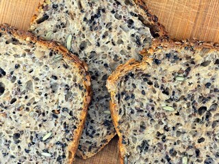 Photo showing freshly baked bread on a wooden board, partially sliced with a knife.