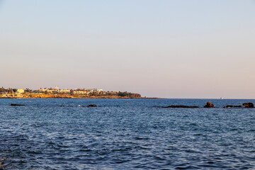 Fototapeta premium Coastal view of Paphos with rocky shoreline and buildings at sunset, Paphos, Cyprus, 23.11.2024